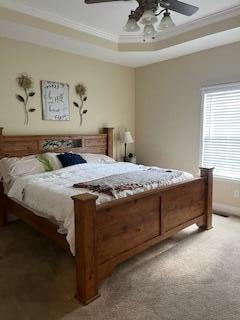 bedroom featuring crown molding, ceiling fan, a raised ceiling, and light colored carpet