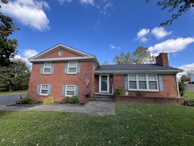 tri-level home featuring a front lawn, brick siding, and a chimney