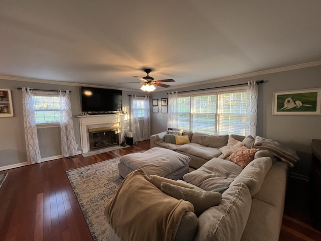 living room featuring wood finished floors, ornamental molding, baseboards, a tiled fireplace, and ceiling fan