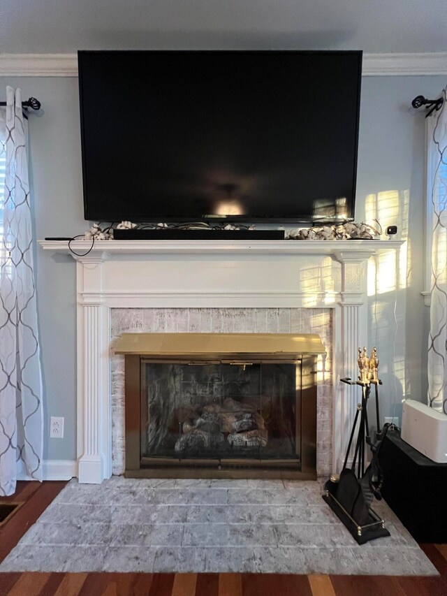 room details with hardwood / wood-style flooring, ornamental molding, and a tiled fireplace