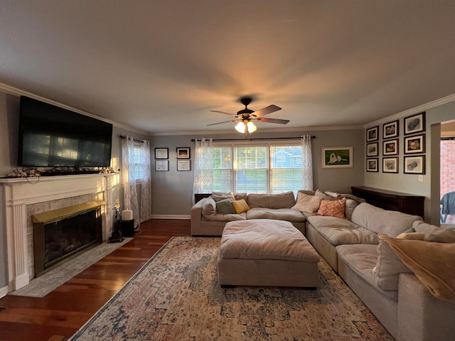 living room featuring ceiling fan, ornamental molding, dark wood-type flooring, and a tiled fireplace