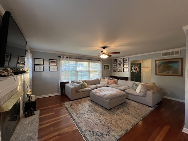living room with a ceiling fan, visible vents, a fireplace, baseboards, and dark wood-style floors