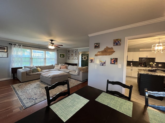 dining area with ceiling fan with notable chandelier, light wood finished floors, and crown molding