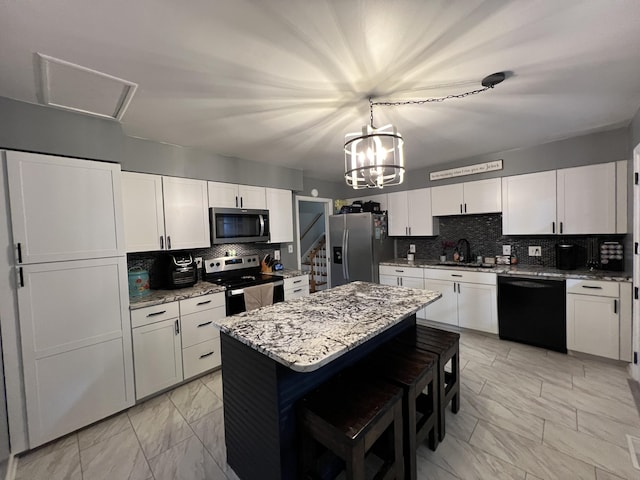 kitchen featuring white cabinets, marble finish floor, a kitchen breakfast bar, tasteful backsplash, and appliances with stainless steel finishes