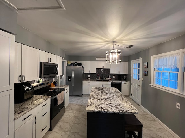 kitchen with backsplash, light stone counters, stainless steel appliances, a center island, and white cabinetry