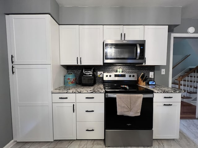 kitchen featuring marble finish floor, decorative backsplash, appliances with stainless steel finishes, and white cabinetry
