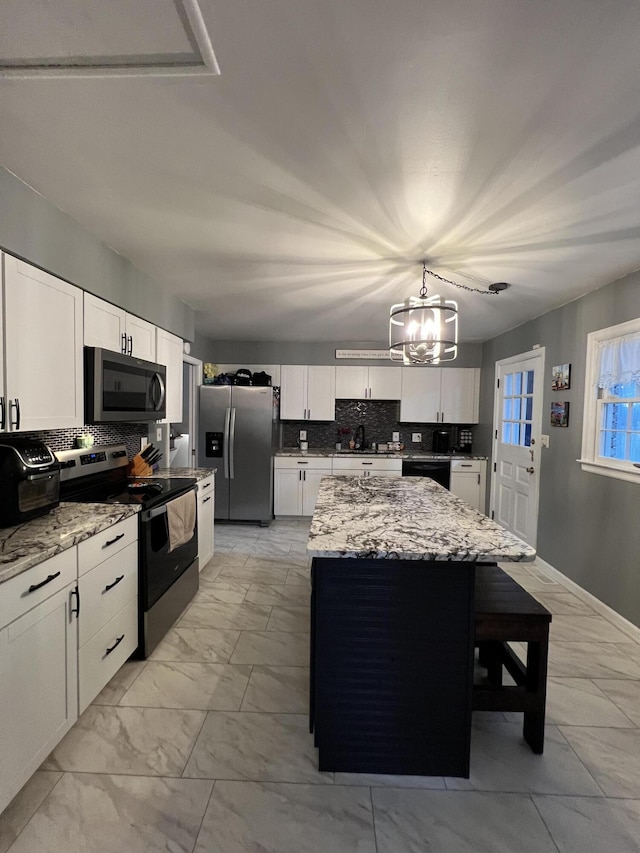 kitchen with marble finish floor, a center island, appliances with stainless steel finishes, and tasteful backsplash