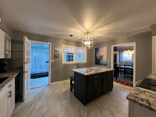 kitchen featuring white cabinetry, light stone counters, dishwasher, and a kitchen island