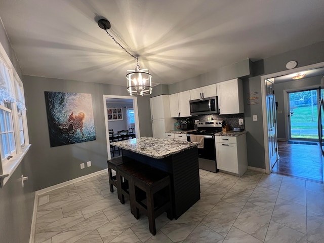 kitchen featuring white cabinets, a center island, stainless steel appliances, and stone counters