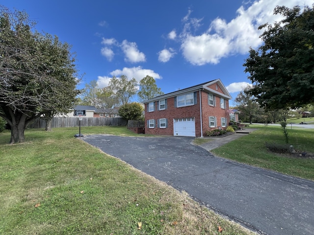 view of side of property featuring fence, brick siding, an attached garage, a lawn, and aphalt driveway