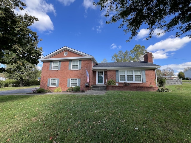 view of front of house with fence, a chimney, brick siding, and a front yard