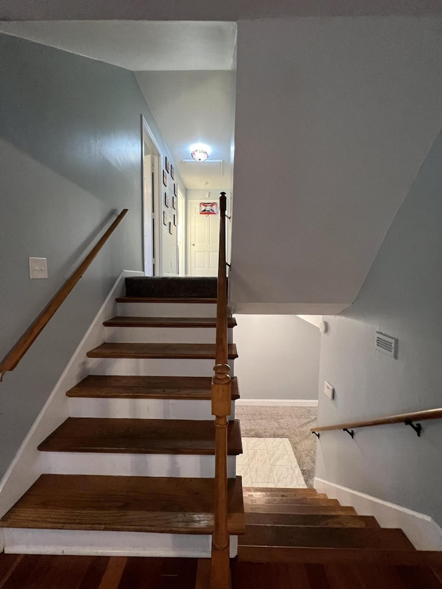 stairway featuring baseboards and visible vents