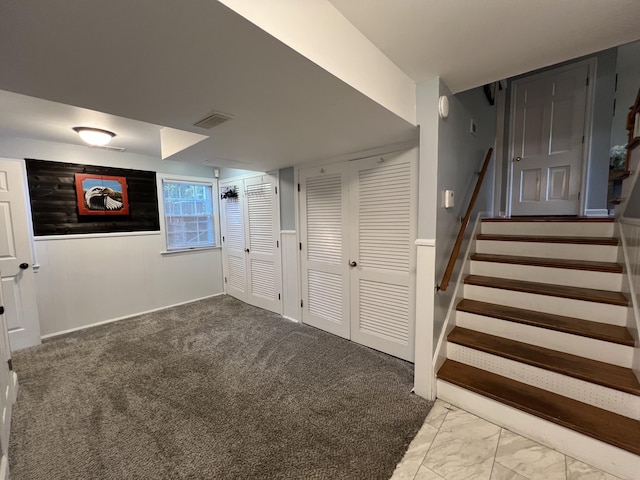 finished basement featuring visible vents, marble finish floor, and stairs