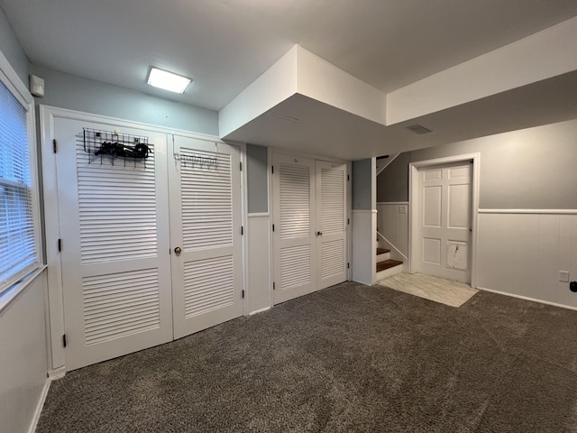 basement with a wainscoted wall, carpet floors, and stairs