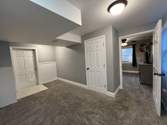 below grade area featuring baseboards, carpet, and ceiling fan