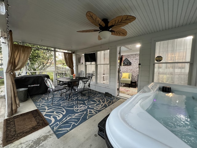 sunroom with a ceiling fan, a hot tub, and outdoor dining space