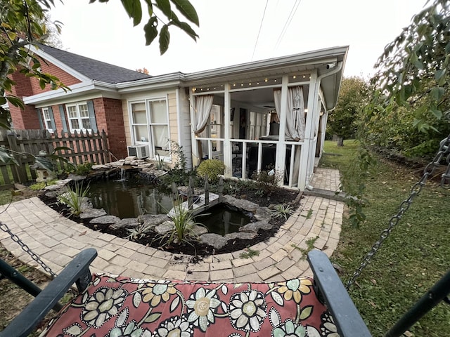 view of side of property featuring fence, brick siding, and a small pond