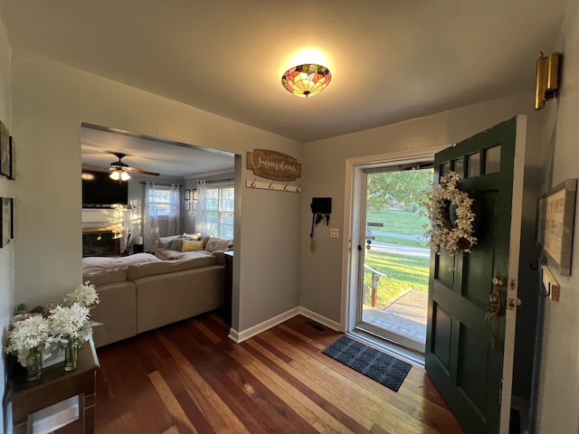 foyer with dark wood finished floors, a ceiling fan, and baseboards
