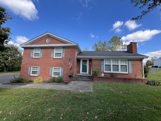 split level home with a chimney, brick siding, and a front yard
