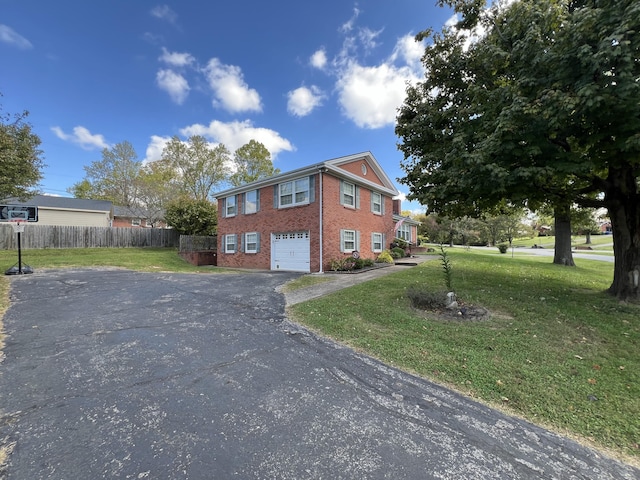 view of property exterior featuring driveway, fence, brick siding, a garage, and a yard