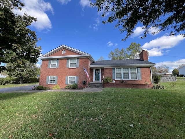 view of front of house featuring brick siding, a front yard, and a chimney