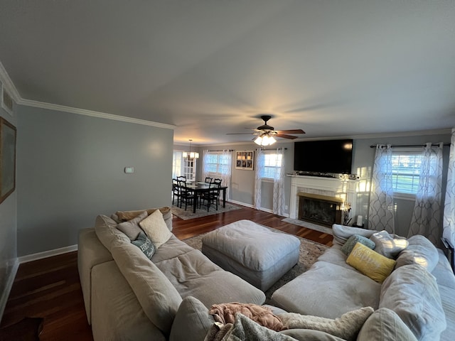 living area featuring a fireplace with flush hearth, baseboards, crown molding, and a healthy amount of sunlight