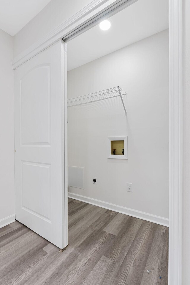 clothes washing area with light hardwood / wood-style floors, electric dryer hookup, and washer hookup