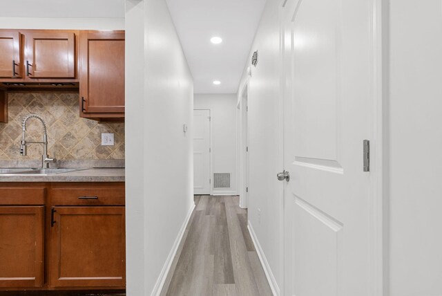 corridor featuring sink and light hardwood / wood-style floors