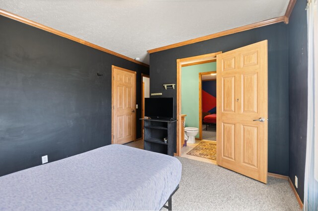 carpeted bedroom with ornamental molding and connected bathroom