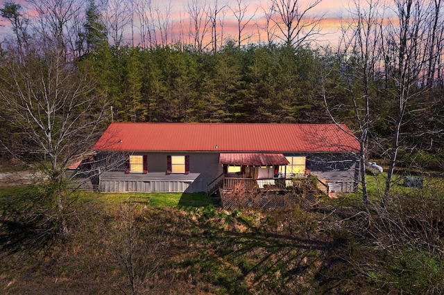 back house at dusk featuring a wooden deck