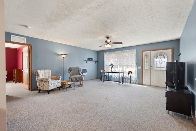 living area with a textured ceiling, heating unit, carpet, and ceiling fan