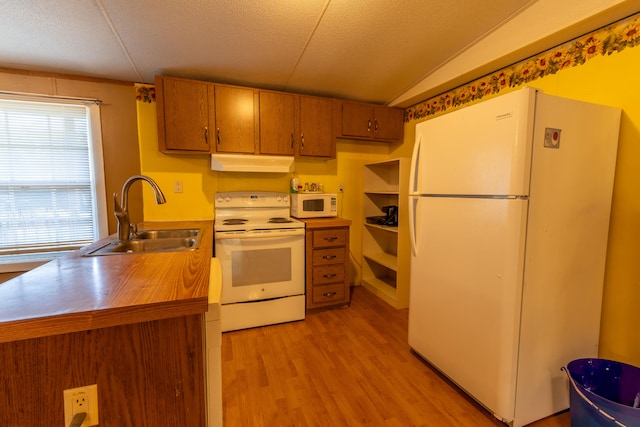 kitchen with light hardwood / wood-style floors, white appliances, vaulted ceiling, sink, and a textured ceiling