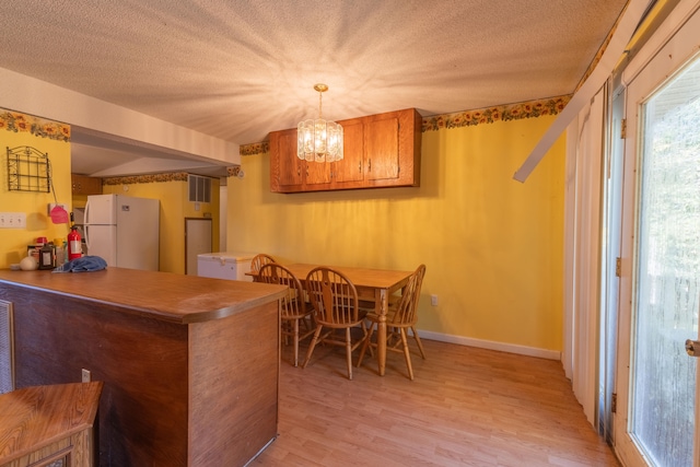 kitchen with kitchen peninsula, a textured ceiling, decorative light fixtures, light wood-type flooring, and white fridge