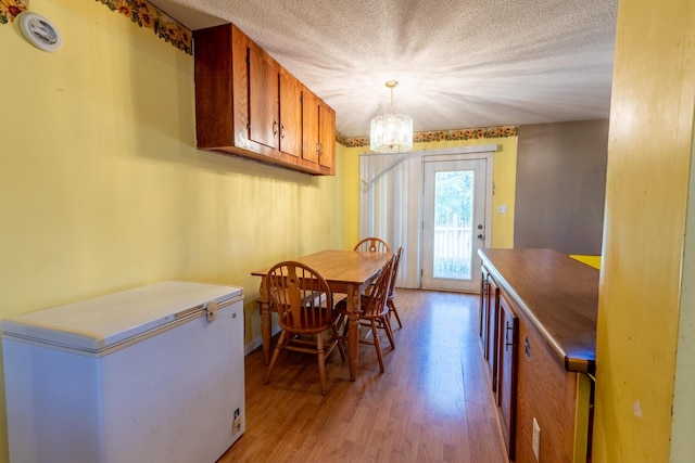 179 Bill Patrick Rd, Whitley City, KY 42653 - dining area featuring a chandelier, light wood-style flooring, and a textured ceiling