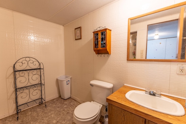 bathroom with a textured ceiling, tile walls, vanity, and toilet