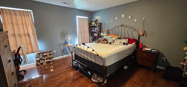 bedroom with a textured ceiling and dark hardwood / wood-style flooring