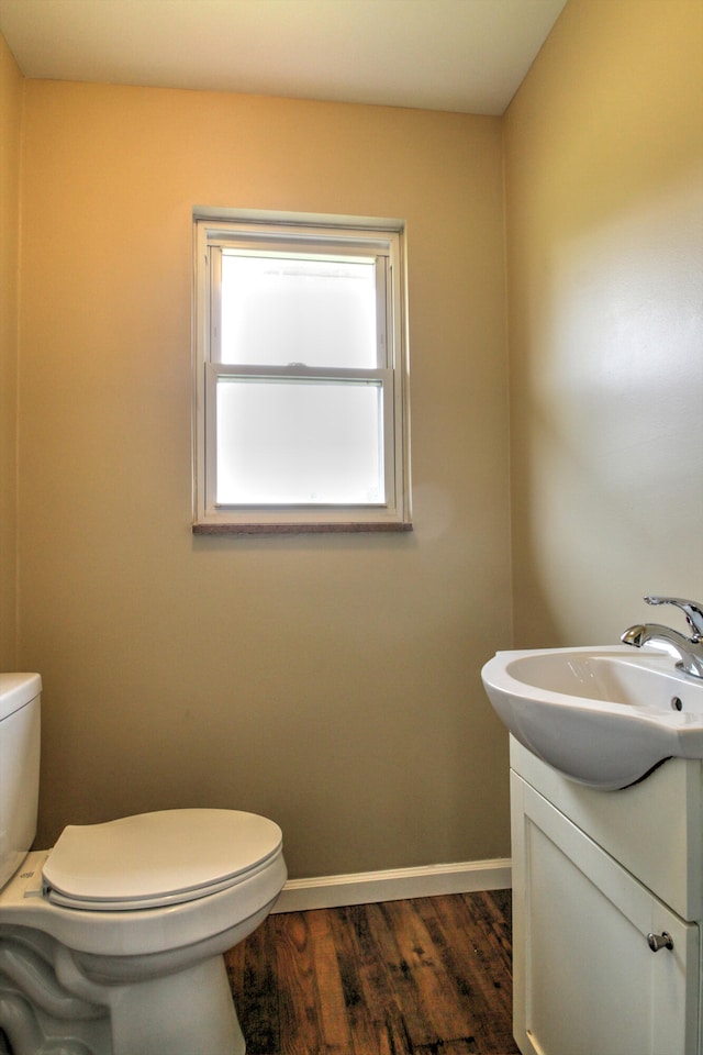 bathroom with toilet, vanity, and wood-type flooring