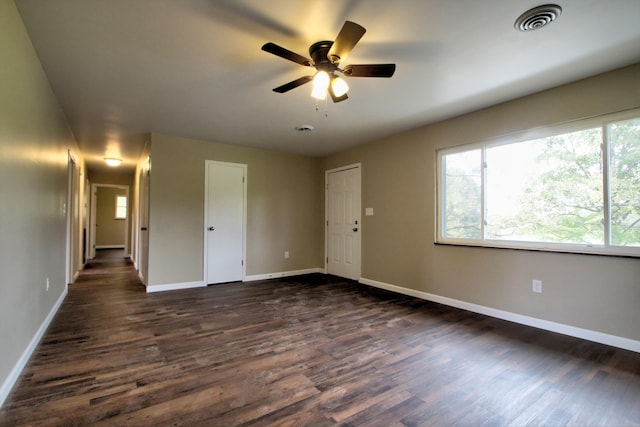 empty room with ceiling fan and dark hardwood / wood-style flooring