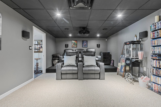 carpeted home theater room featuring a drop ceiling