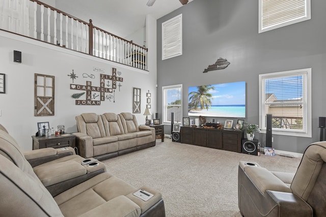 carpeted living room with a high ceiling, ceiling fan, and plenty of natural light