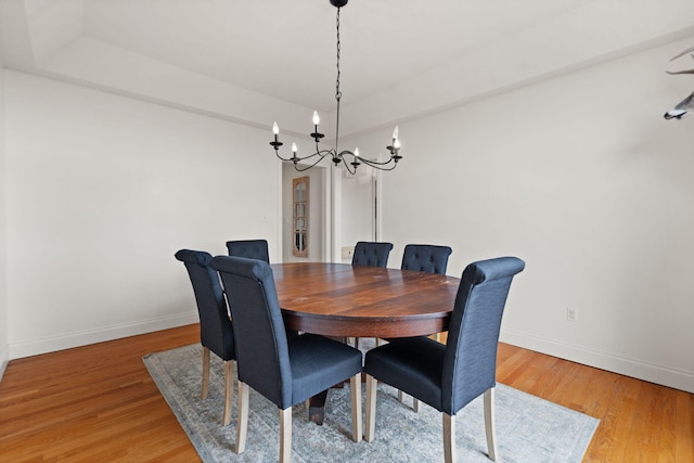 dining room with a tray ceiling, a chandelier, and wood-type flooring