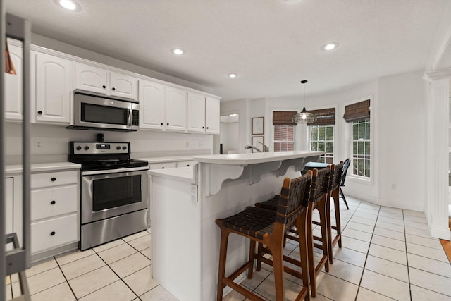 kitchen featuring pendant lighting, white cabinets, stainless steel appliances, and a kitchen island