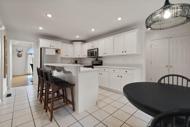 kitchen featuring black electric range oven, light tile patterned floors, a kitchen island, and white cabinets