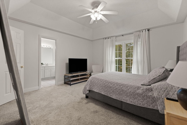 bedroom featuring connected bathroom, ceiling fan, light carpet, and a raised ceiling