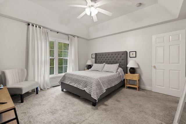 carpeted bedroom with ceiling fan and a tray ceiling