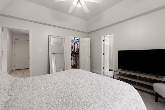 bedroom featuring ceiling fan, connected bathroom, a closet, light tile patterned flooring, and a walk in closet