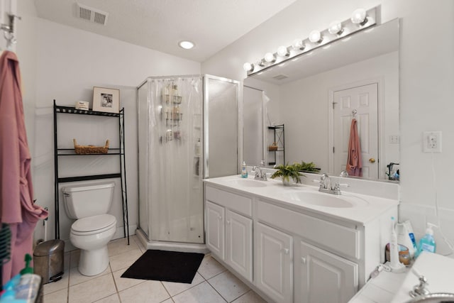 bathroom featuring toilet, vanity, tile patterned floors, and a shower with door