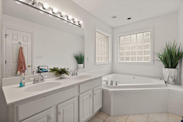 bathroom featuring vanity, a textured ceiling, tiled tub, and tile patterned floors