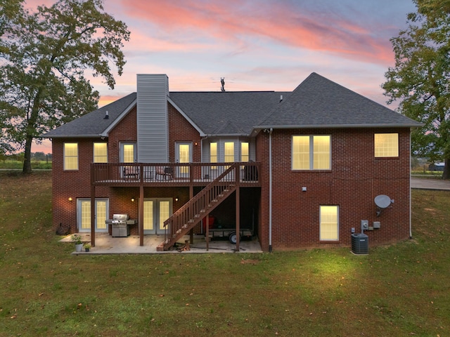 back house at dusk with a patio area, central AC, a wooden deck, and a lawn