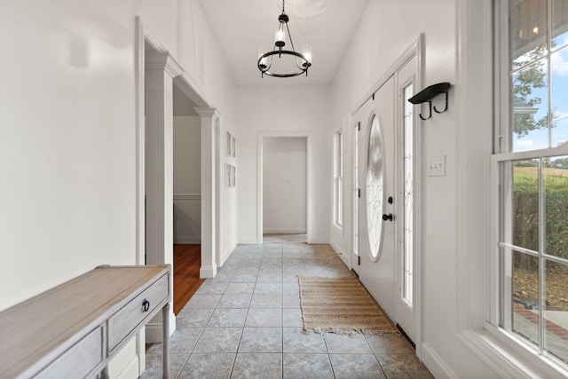 entryway with an inviting chandelier and light tile patterned flooring